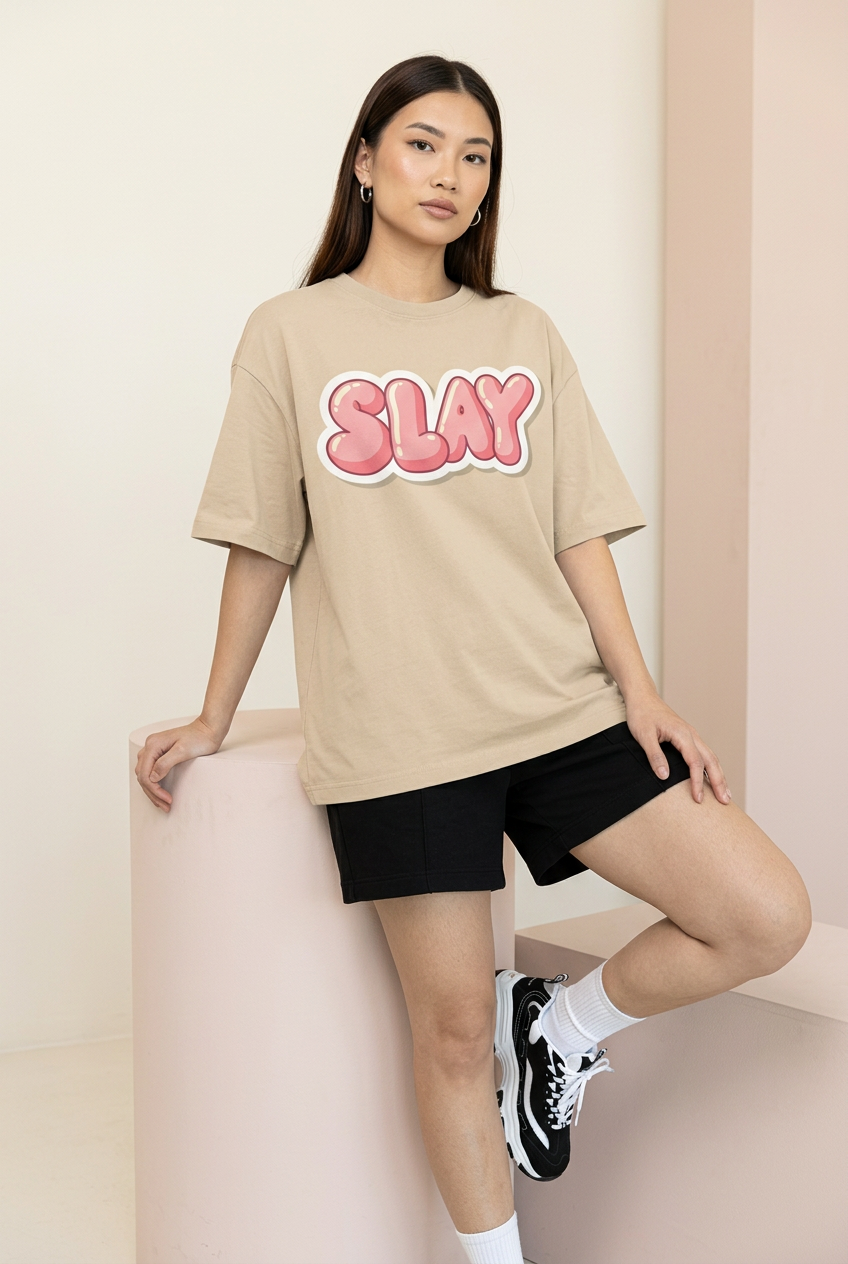 Beige Pink Slay oversized tee, leaning model pose